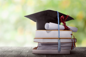 Graduation hat with degree paper on a stack of books