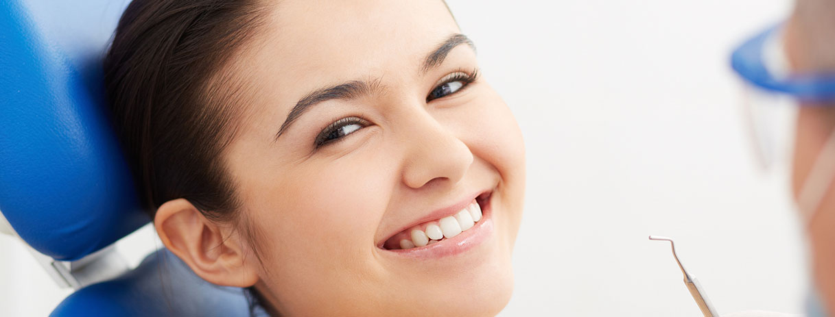 Stock image of a girl smiling by sitting in dental chair